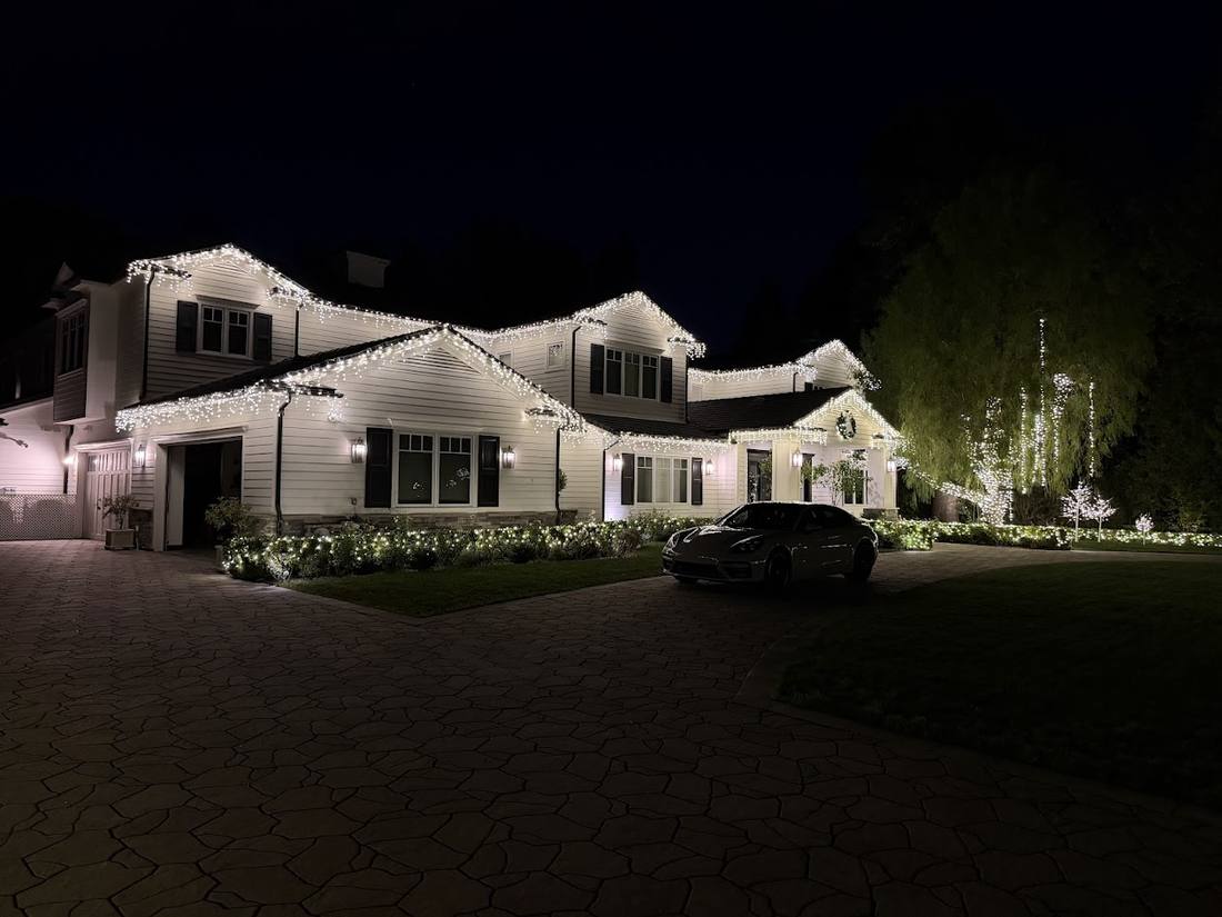 Two-story home with warm white icicle lights along the roofline